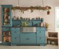 Blue kitchen cabinetry with green plants.